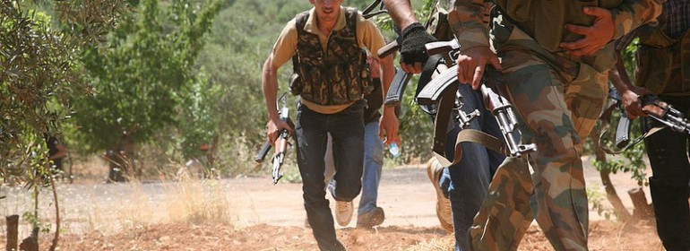 Syrian rebels from the “Al-Qasas Brigade” or “Justice Brigade” run through an olive grove to avoid Syrian Army snipers as they travel between villages on foot in the northwestern Jabal al-Zawiya area.