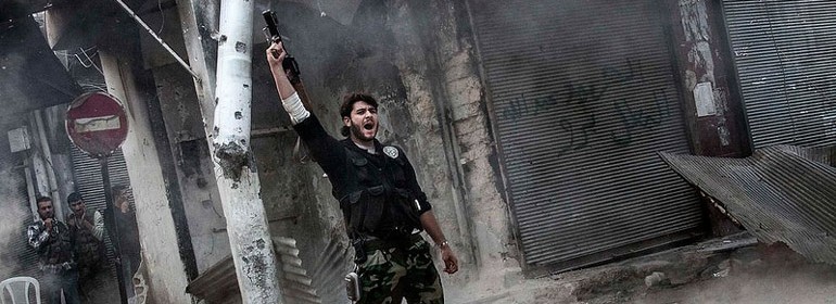 A rebel fighter signals victory after he fires a shoulder-fired missile toward a building where Syrian troops loyal to President Bashar Assad were hiding in the Jedida district of Aleppo, Syria on November 4, 2012.